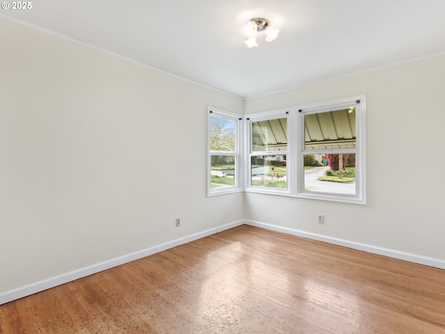 empty room with crown molding, baseboards, and wood finished floors