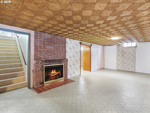 unfurnished living room with stairs, tile patterned floors, wallpapered walls, and a fireplace