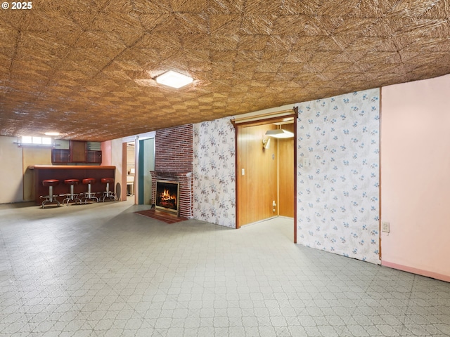 below grade area with a brick fireplace, tile patterned floors, baseboards, and a bar