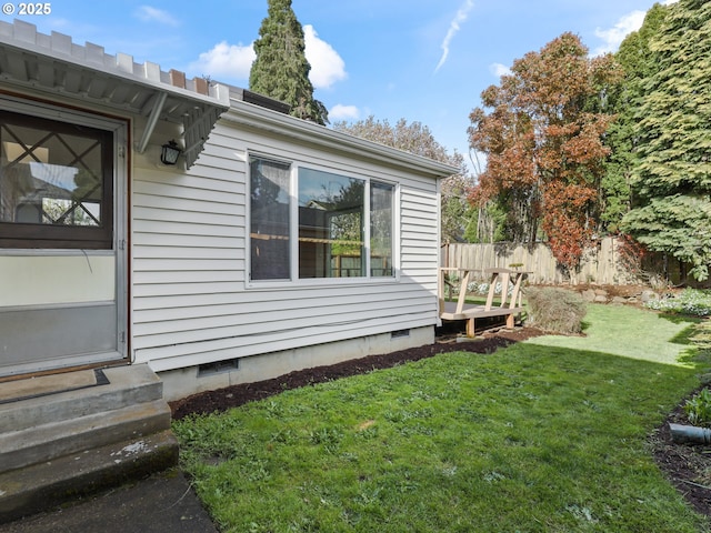 view of property exterior featuring a lawn, crawl space, fence, and entry steps