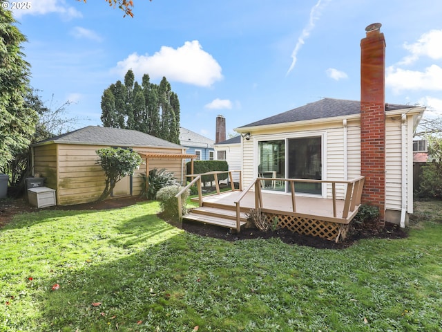 back of property with an outbuilding, a wooden deck, a yard, and a chimney