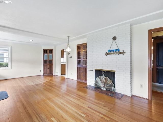 unfurnished living room featuring baseboards, arched walkways, wood finished floors, and a fireplace