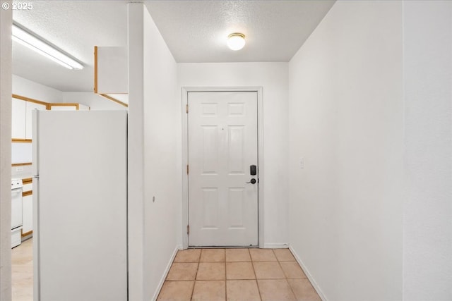 doorway to outside featuring light tile patterned flooring, a textured ceiling, and baseboards