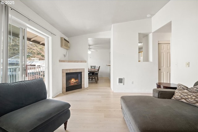 living area with a ceiling fan, a wall mounted AC, heating unit, light wood-style floors, and lofted ceiling