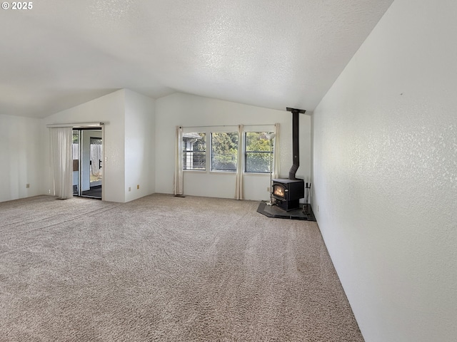 543 Linda Ln, Brookings, OR 97415 - unfurnished living room featuring lofted ceiling, a wood stove, carpet, and a textured ceiling