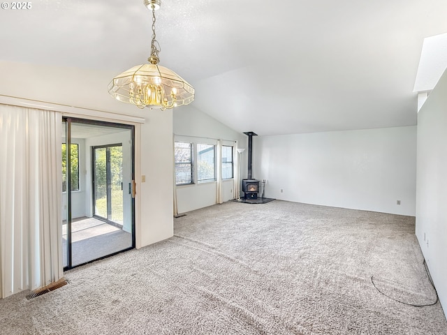 543 Linda Ln, Brookings, OR 97415 - unfurnished living room featuring vaulted ceiling, carpet, a wood stove, and a chandelier