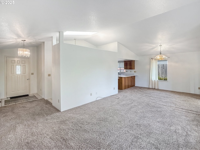 543 Linda Ln, Brookings, OR 97415 - unfurnished living room featuring lofted ceiling, a chandelier, light colored carpet, plenty of natural light, and a skylight