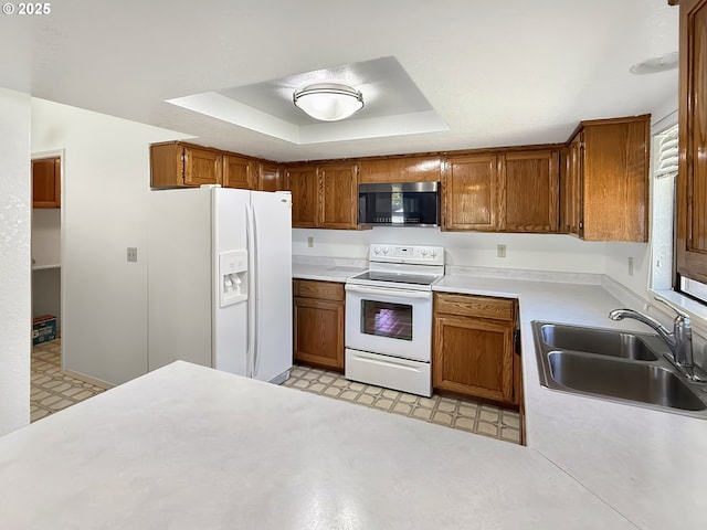 543 Linda Ln, Brookings, OR 97415 - kitchen featuring white appliances, light flooring, a sink, a tray ceiling, and brown cabinetry
