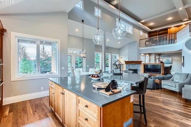 kitchen featuring dark countertops, open floor plan, hanging light fixtures, and an island with sink