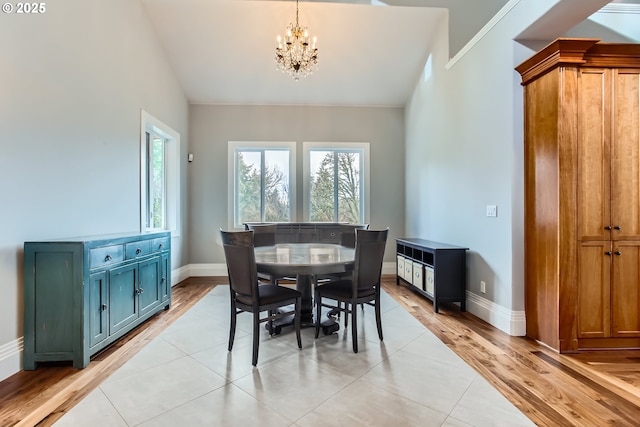 dining area featuring a chandelier, vaulted ceiling, baseboards, and light wood-style floors