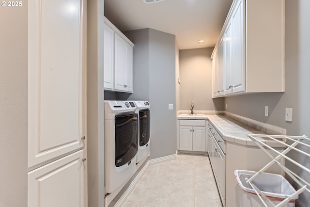 washroom with light tile patterned floors, washing machine and dryer, recessed lighting, a sink, and cabinet space