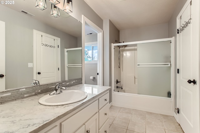 full bath with combined bath / shower with glass door, visible vents, vanity, and tile patterned floors