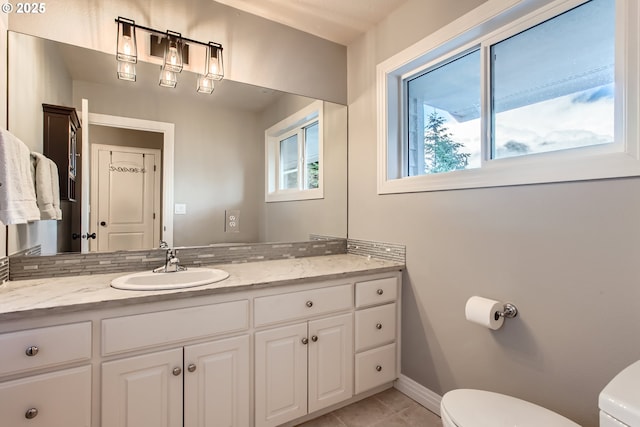 bathroom with tile patterned flooring, vanity, toilet, and baseboards