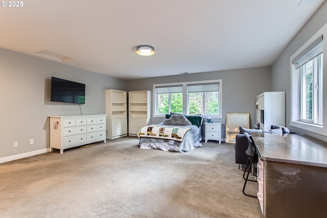 bedroom with light carpet, attic access, and baseboards