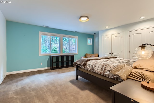 carpeted bedroom featuring multiple closets, recessed lighting, visible vents, and baseboards