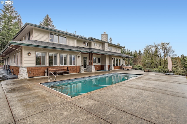 back of property with a patio, a chimney, and an outdoor pool