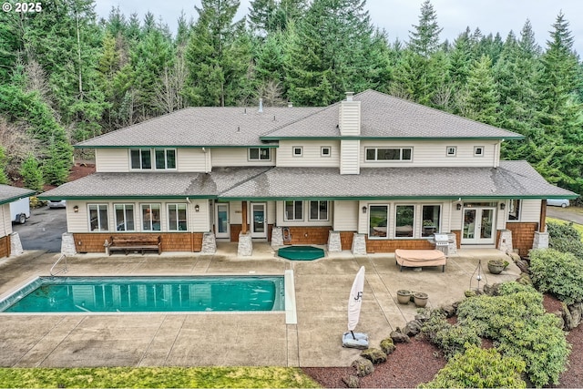 rear view of house with a fenced in pool, french doors, a patio area, and a chimney