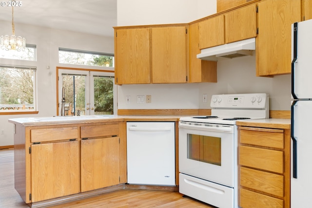 kitchen with light countertops, white appliances, light wood-type flooring, pendant lighting, and under cabinet range hood