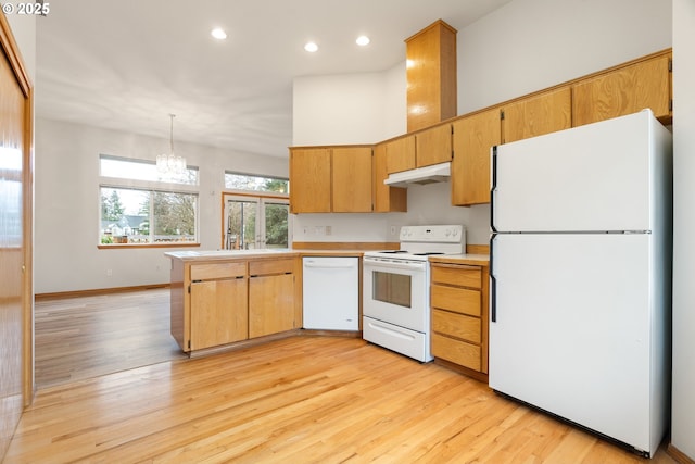 kitchen featuring light countertops, light wood-style flooring, white appliances, decorative light fixtures, and under cabinet range hood