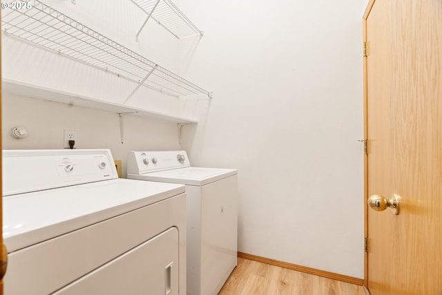 clothes washing area with laundry area, independent washer and dryer, light wood-type flooring, and baseboards