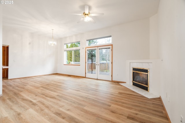 unfurnished living room with baseboards, light wood finished floors, a fireplace, and french doors