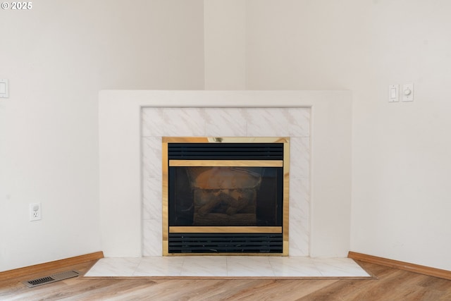 details featuring baseboards, visible vents, a fireplace, and wood finished floors