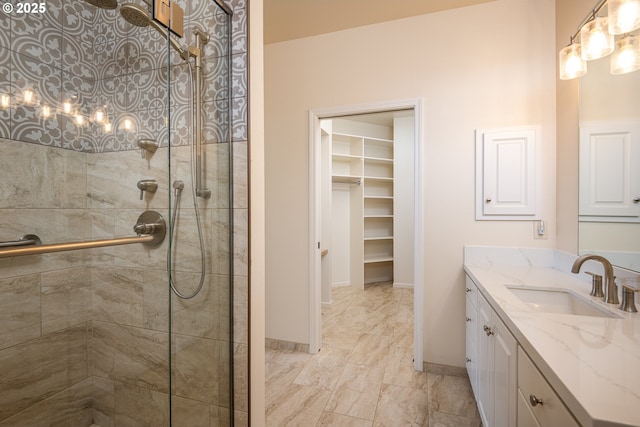 bathroom with a tile shower, vanity, baseboards, marble finish floor, and a spacious closet