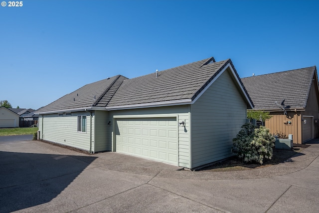exterior space with an attached garage, driveway, and a tile roof