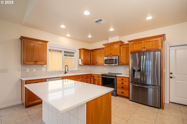 kitchen featuring visible vents, brown cabinetry, a sink, light tile patterned floors, and stainless steel appliances
