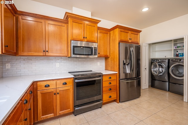 kitchen featuring independent washer and dryer, brown cabinets, light countertops, stainless steel appliances, and light tile patterned floors