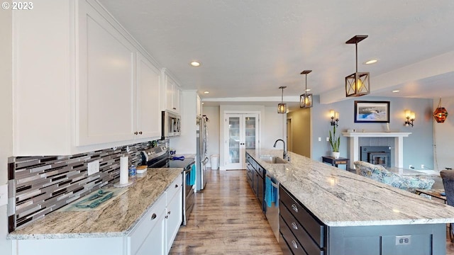 97997 Olsen Ln, Brookings, OR 97415 - kitchen with appliances with stainless steel finishes, a sink, white cabinetry, light wood-style floors, and backsplash