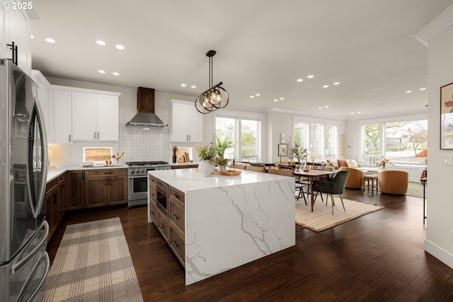 kitchen with tasteful backsplash, a center island, stainless steel appliances, wall chimney range hood, and dark wood-style flooring