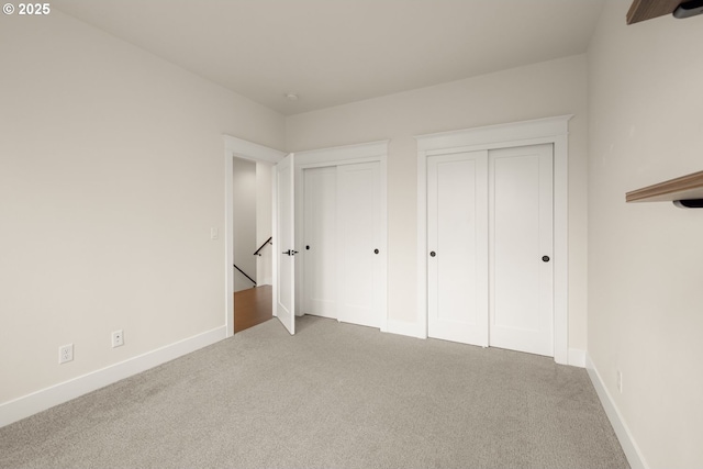 unfurnished bedroom featuring baseboards, multiple closets, and carpet floors