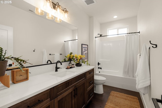 full bathroom with visible vents, shower / bath combo with shower curtain, toilet, wood finished floors, and vanity