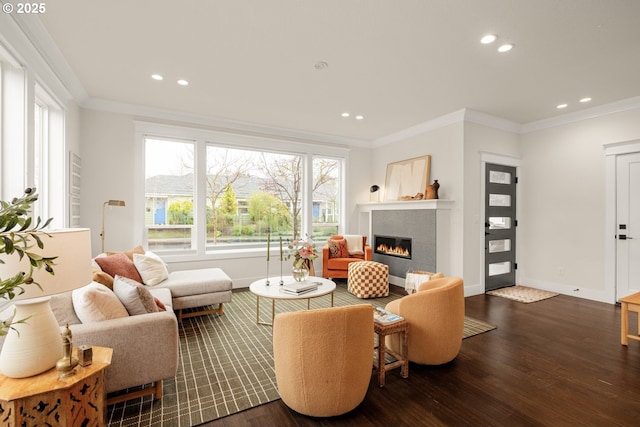 living room with a tiled fireplace, wood finished floors, and ornamental molding