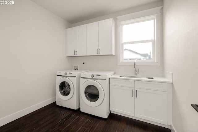 washroom with a sink, baseboards, washing machine and dryer, cabinet space, and dark wood-style flooring