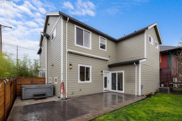 back of house with a lawn, a hot tub, a patio, and fence