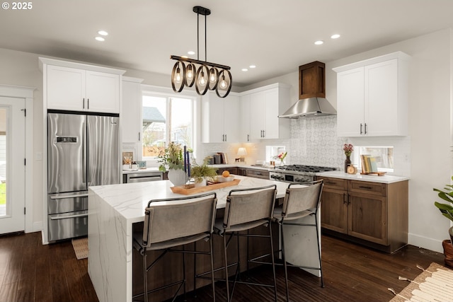 kitchen featuring backsplash, appliances with stainless steel finishes, dark wood-style flooring, and wall chimney range hood