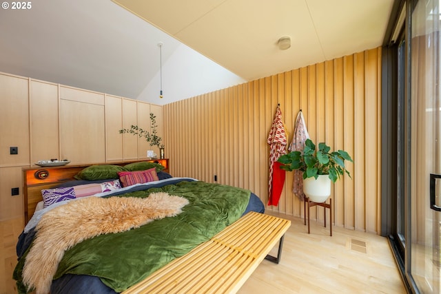 bedroom featuring light wood finished floors, vaulted ceiling, and visible vents