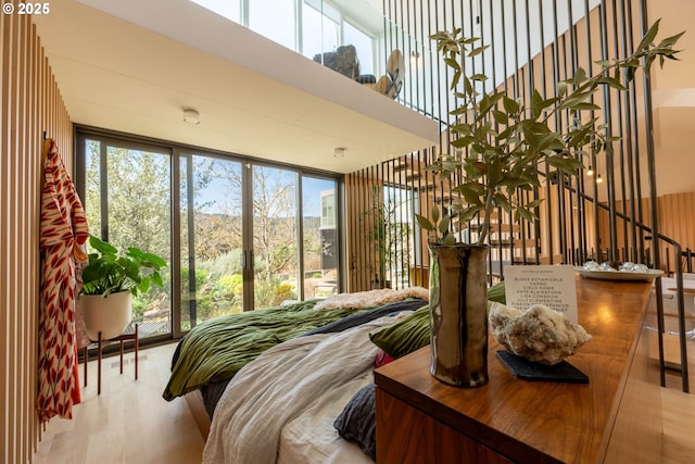 bedroom with a high ceiling, wood finished floors, and multiple windows