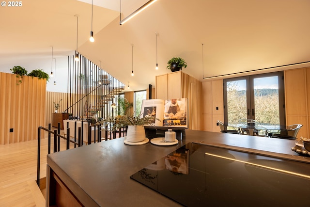 kitchen with dark countertops, light wood finished floors, a towering ceiling, and french doors
