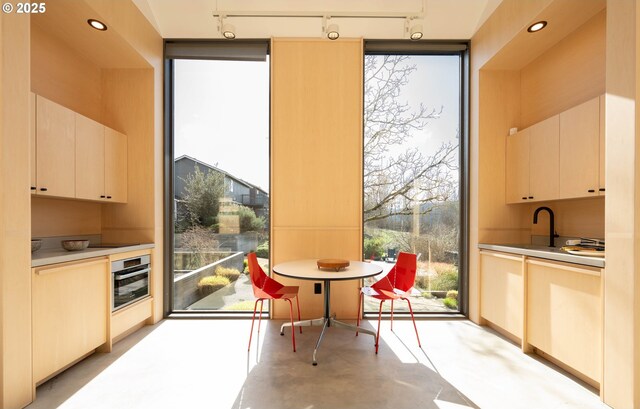 kitchen featuring track lighting, stainless steel oven, concrete flooring, and a sink