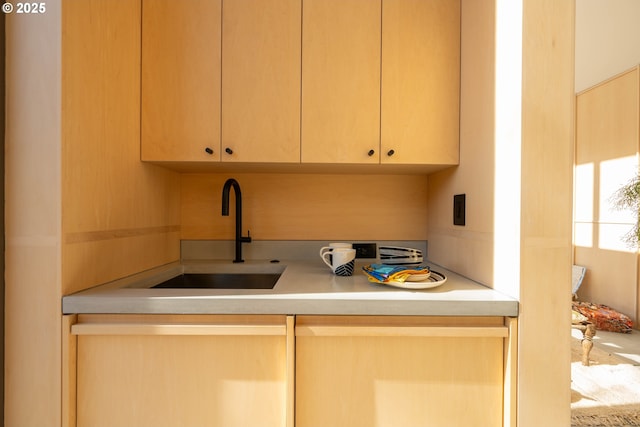kitchen featuring light countertops, light brown cabinetry, and a sink