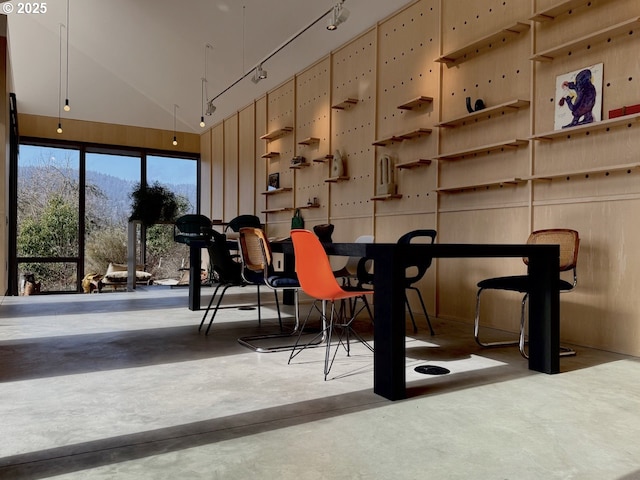 dining area featuring rail lighting, vaulted ceiling, and finished concrete floors