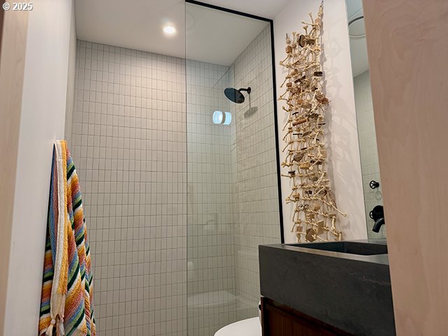 bathroom featuring toilet, vanity, and a tile shower