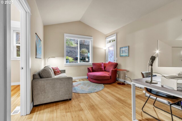 living area with light wood-style flooring, lofted ceiling, and baseboards