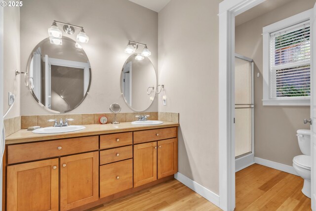 full bath with toilet, wood finished floors, and a shower stall