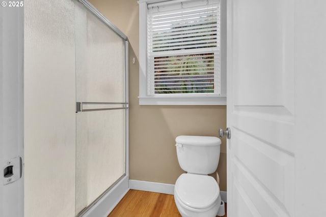 bathroom with baseboards, a stall shower, plenty of natural light, and toilet