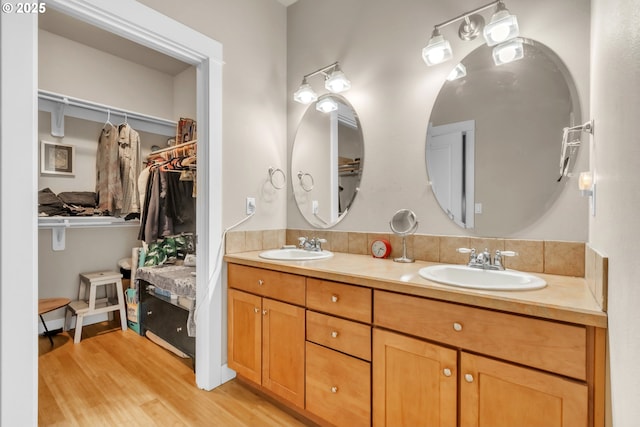 full bath with wood finished floors, a spacious closet, and double vanity