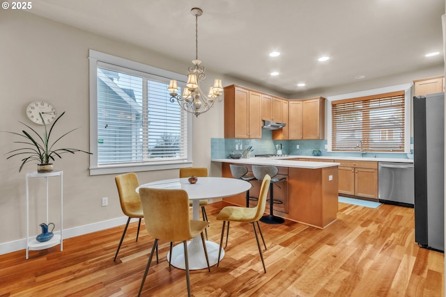 kitchen with appliances with stainless steel finishes, decorative backsplash, light wood finished floors, light brown cabinets, and recessed lighting